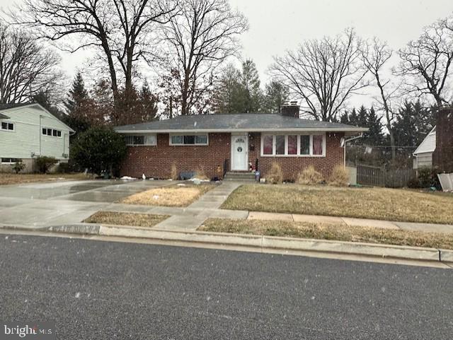 view of front of property featuring brick siding, concrete driveway, and a chimney