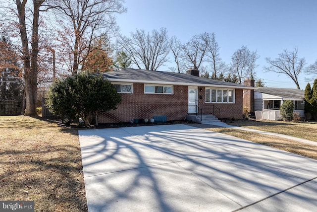 single story home featuring a front yard, brick siding, and a chimney