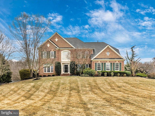 georgian-style home featuring a front yard, crawl space, and brick siding