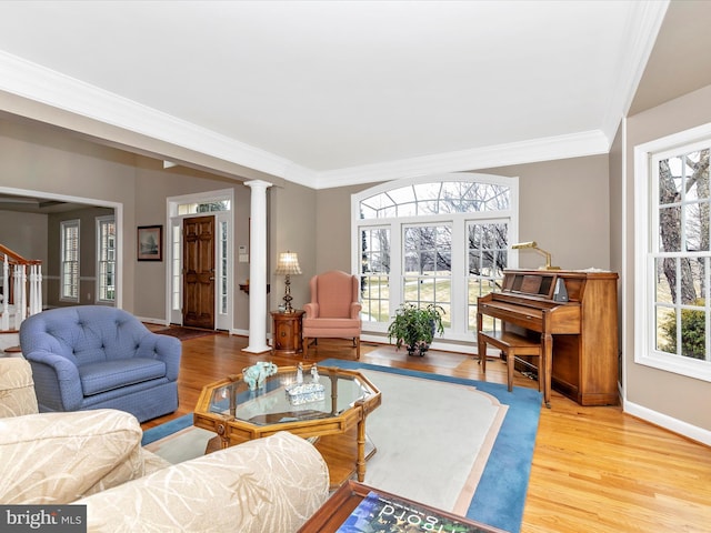 living area featuring a wealth of natural light, decorative columns, and wood finished floors