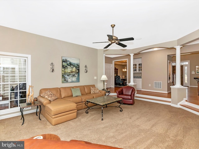 carpeted living area featuring visible vents, baseboards, decorative columns, and a ceiling fan