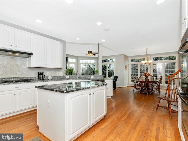 kitchen featuring black gas cooktop, light wood-type flooring, white cabinets, and dark stone countertops