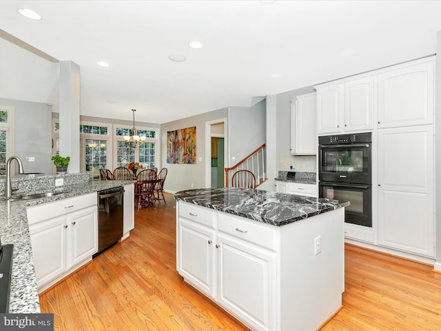 kitchen featuring black appliances, light wood-style flooring, white cabinetry, and a sink