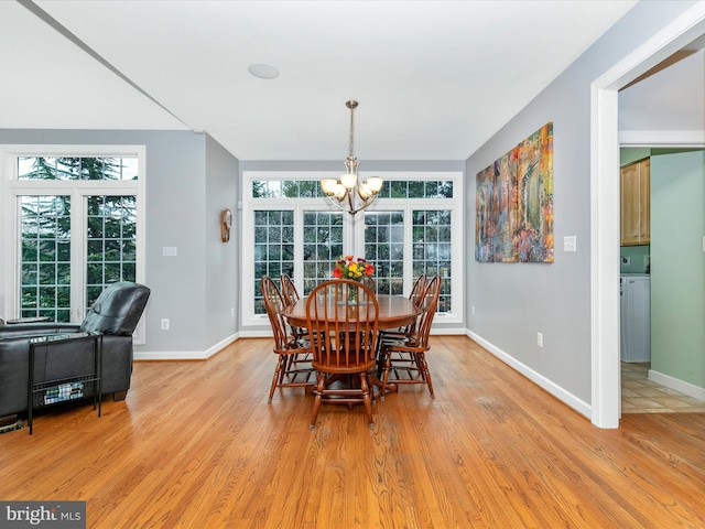 dining space featuring baseboards, light wood finished floors, and an inviting chandelier