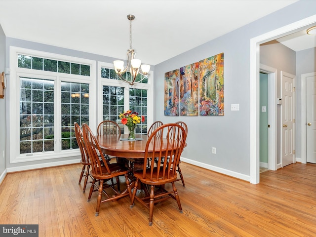 dining room featuring light wood-style flooring, baseboards, and a notable chandelier