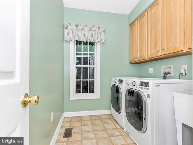 clothes washing area featuring washer and clothes dryer, cabinet space, visible vents, and baseboards