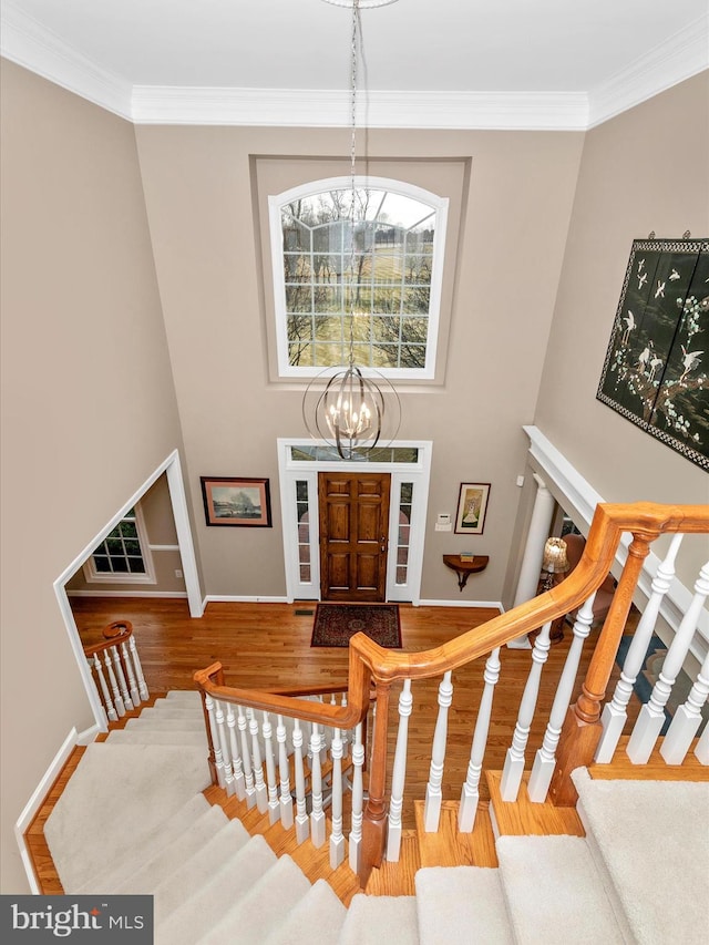 entryway with a chandelier, ornamental molding, stairway, and wood finished floors