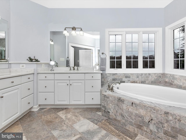 bathroom with stone finish floor, vanity, and a bath