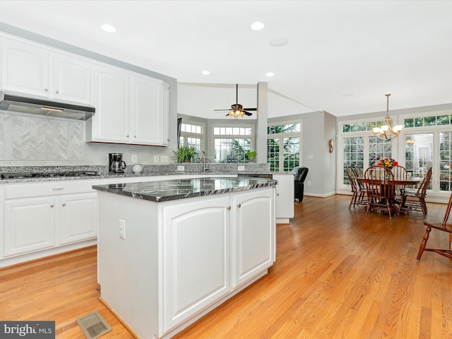 kitchen with light wood-type flooring, visible vents, under cabinet range hood, and gas stovetop