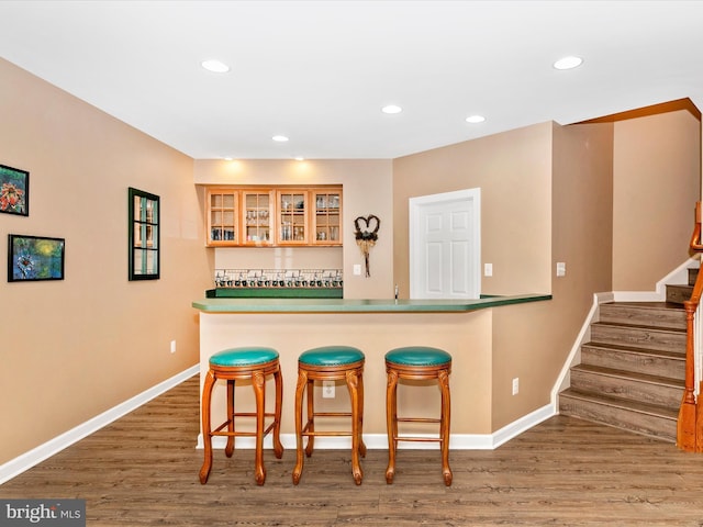 kitchen featuring recessed lighting, baseboards, a kitchen breakfast bar, and wood finished floors