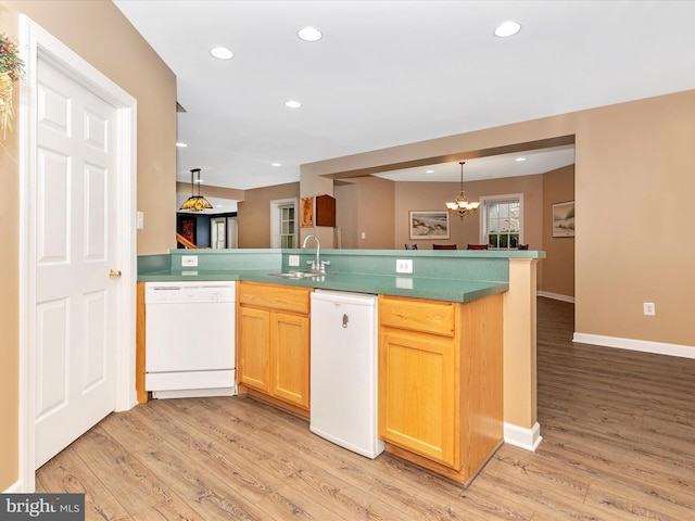 kitchen with dishwasher, a peninsula, light wood-type flooring, and a sink