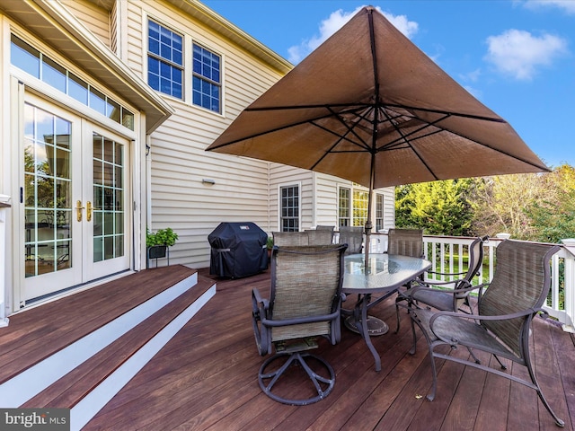 wooden deck with outdoor dining space, area for grilling, and french doors