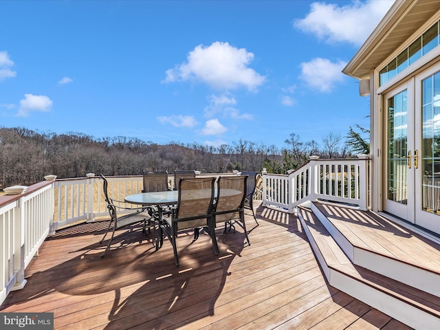 wooden deck featuring a forest view and outdoor dining area