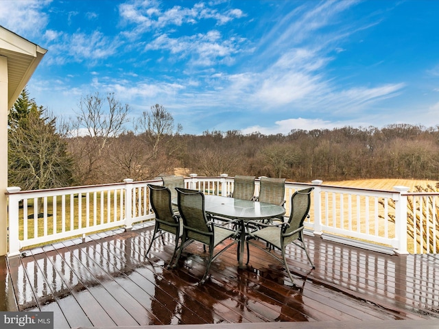 wooden terrace featuring a forest view and outdoor dining area