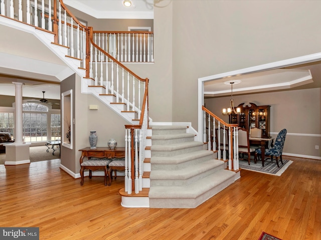 staircase featuring crown molding, a high ceiling, baseboards, and wood finished floors