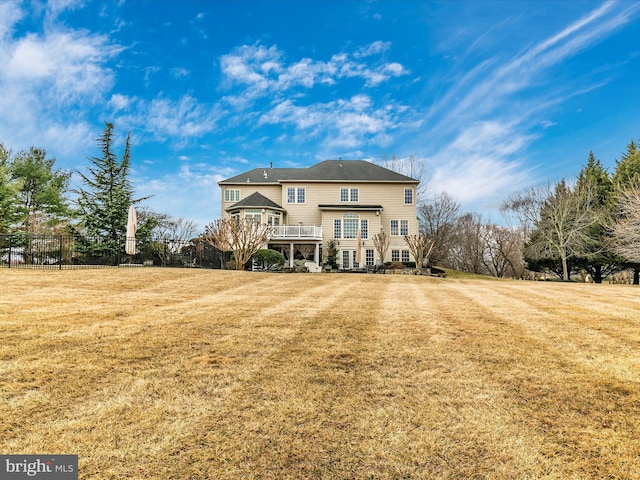 back of property with fence, a deck, and a yard