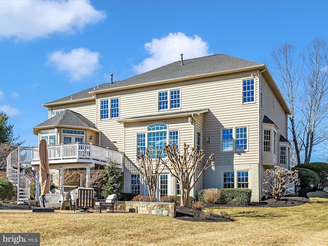 back of property featuring brick siding, a yard, stairway, a patio area, and a deck