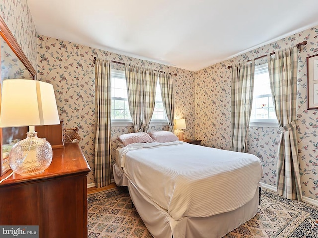 bedroom with baseboards, multiple windows, and wallpapered walls