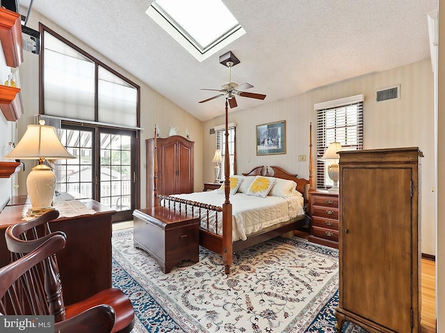 bedroom featuring a textured ceiling, multiple windows, lofted ceiling with skylight, and visible vents