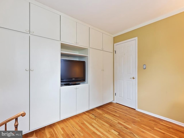 unfurnished bedroom featuring crown molding, light wood-style flooring, and baseboards