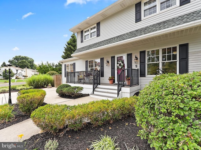 entrance to property with a shingled roof and covered porch