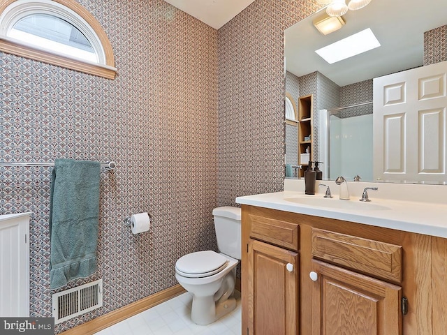 bathroom featuring toilet, a skylight, visible vents, a shower with door, and wallpapered walls