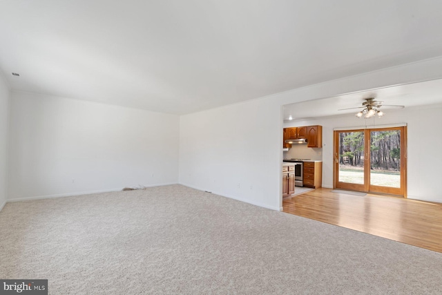 unfurnished living room with light wood-type flooring, a ceiling fan, and light colored carpet