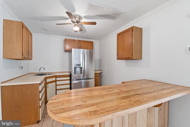 kitchen featuring crown molding, visible vents, a sink, stainless steel fridge, and a peninsula