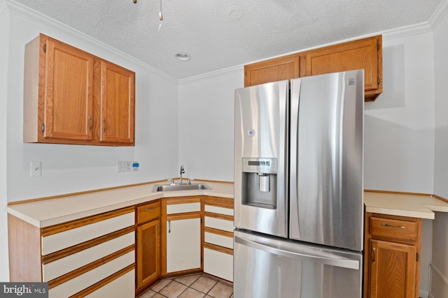 kitchen with stainless steel fridge with ice dispenser, ornamental molding, light countertops, a sink, and light tile patterned flooring