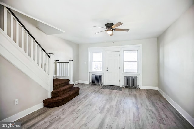 foyer featuring radiator, stairs, baseboards, and wood finished floors