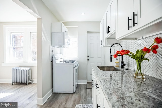 kitchen with light stone counters, a sink, tasteful backsplash, white appliances, and radiator