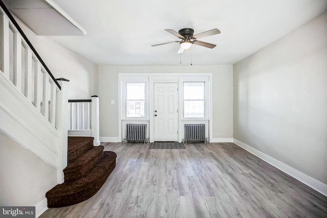 entryway with baseboards, radiator, wood finished floors, and stairs