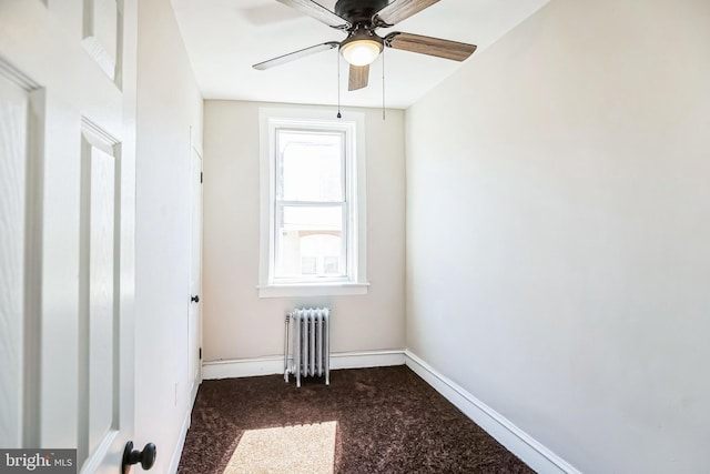 empty room with radiator, baseboards, and dark carpet