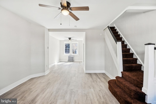 interior space with stairs, radiator, wood finished floors, and baseboards