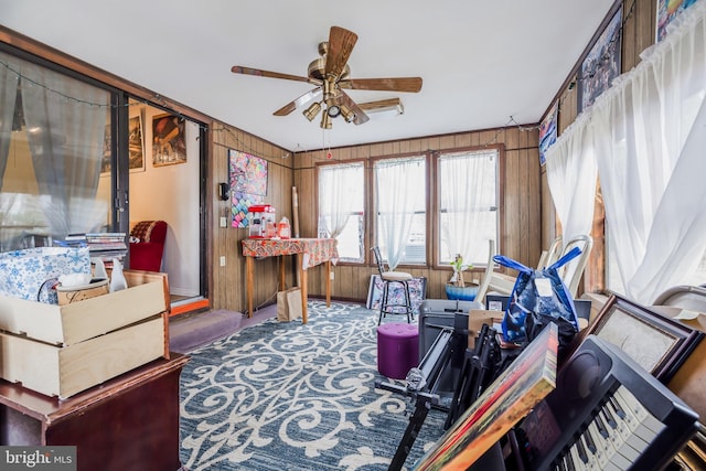 interior space with wood walls, ceiling fan, and carpet flooring