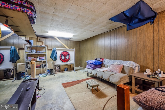 living room with wooden walls and unfinished concrete flooring