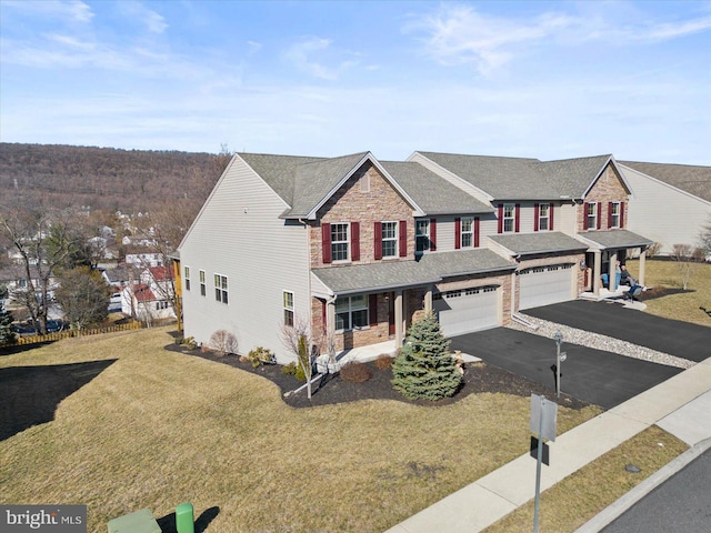 view of front of property featuring a front yard, stone siding, driveway, and a shingled roof