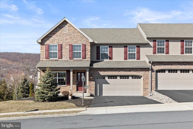 view of front of home featuring stone siding, an attached garage, driveway, and a shingled roof