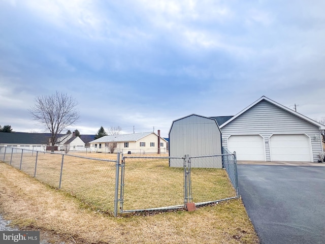 view of yard with driveway, a garage, an outbuilding, a gate, and fence