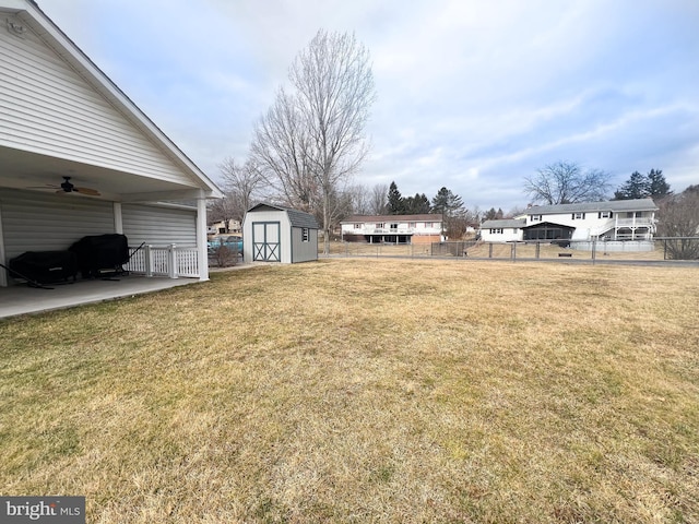 view of yard featuring an outbuilding, a ceiling fan, a patio area, fence, and a shed