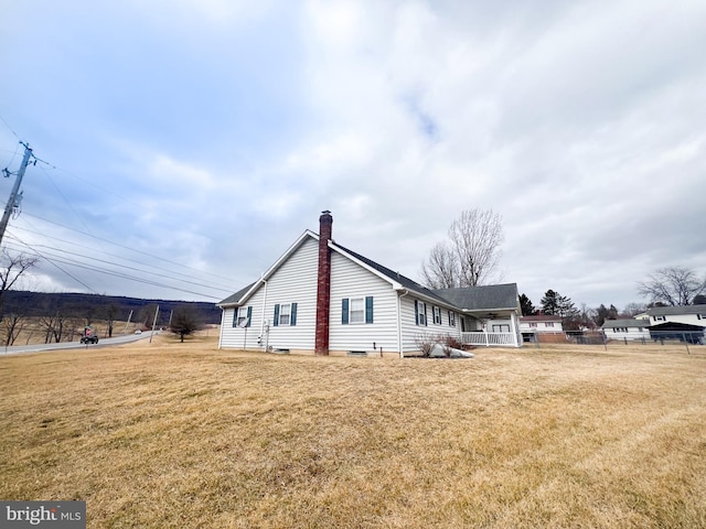 view of side of home featuring a yard, a chimney, and fence