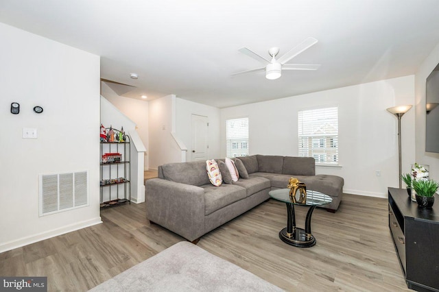 living room featuring baseboards, visible vents, ceiling fan, wood finished floors, and stairs