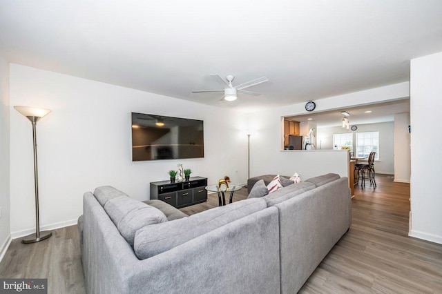 living room with ceiling fan, light wood-style flooring, and baseboards