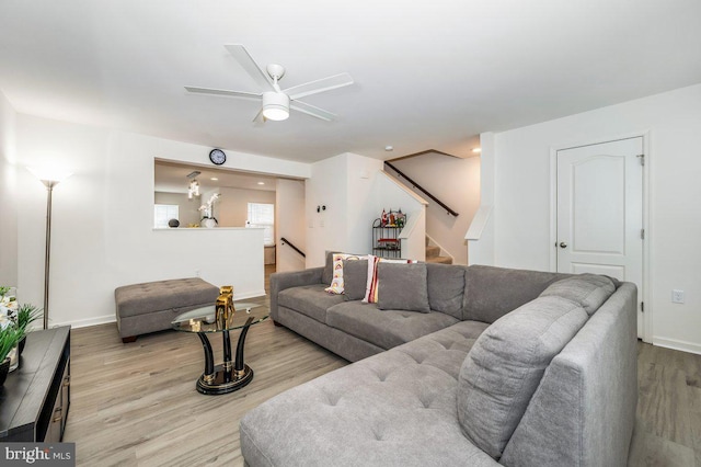 living room with ceiling fan, wood finished floors, stairs, and baseboards