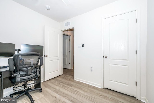 home office featuring light wood-type flooring, visible vents, and baseboards