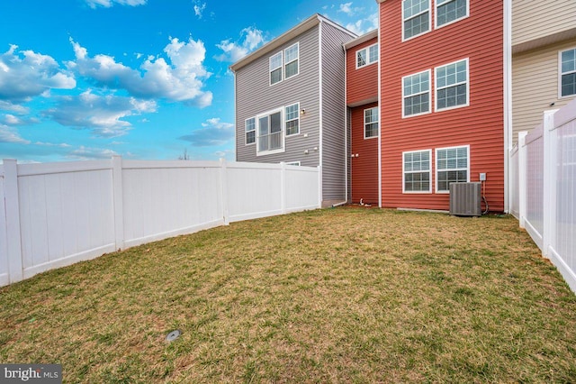 back of property with a fenced backyard, cooling unit, and a yard