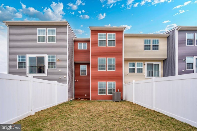 rear view of property with a yard, central AC unit, and a fenced backyard