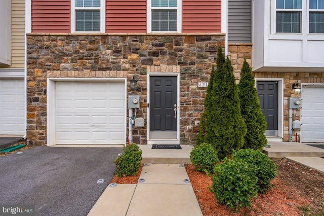 view of exterior entry with a garage and stone siding