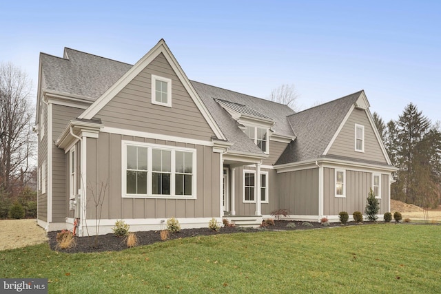 view of front of property with board and batten siding, a front lawn, and roof with shingles