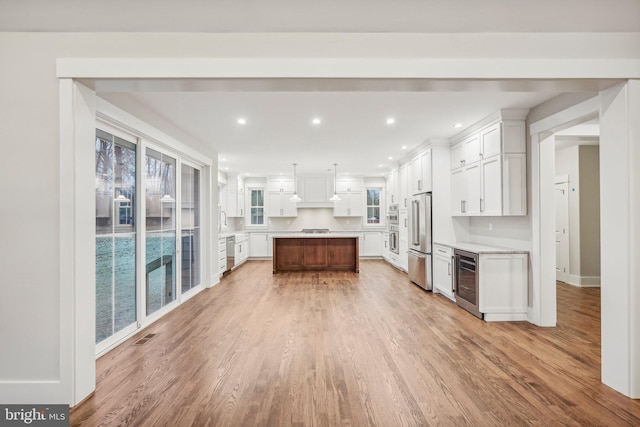 kitchen with beverage cooler, white cabinets, stainless steel appliances, and light countertops